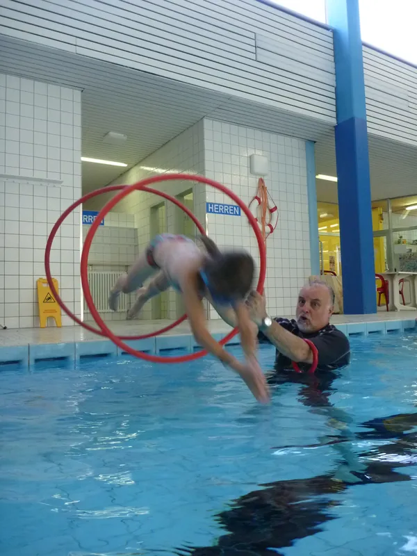 Gründer Wolfgang Weiss im Wasser – ein Kind springt durch einen Reifen auf ihn zu